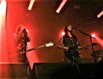 Oh Mann, vierzig Jahre ist es dieses Jahr her, als ich das Debütalbum von W.A.S.P. als Weihnachtsgeschenk meiner Schwester erhielt. Die Musik hatte mich förmlich vom Stuhl gehauen. Was für eine Power!! Das Skandal-Image tat ihr Übriges dazu und bis heute zähle ich mich als Anhänger der Band, wenn auch zeitweise die Musik von dem abwich, was so meine Hausmannkost darstellte. 1986 sah ich sie dann zum ersten Mal als Support für Iron Maiden auf deren „Somewhere In Time" - Tour.  Vier Dekaden nach dem Erstlingswerk: W.A.S.P.-Chef Blackie Lawless ist, wie es bei so vielen Formationen von damals der Fall ist, als einziges Mitglied der ersten Besetzung noch an Bord. Der Hüne ist mit uns Old- School-Metal-Fans alt geworden und wir Fans sind froh, dass er immer noch am Start ist. Leadgitarrist Chris Holmes, der markanteste Mitspieler der US-amerikanischen Truppe hat sich vor vielen Jahren endgültig vom Chef sowie Gefolge getrennt und ist seitdem solo unterwegs. Viel schmutzige Wäsche wurde damals bei der letzten Trennung gewaschen, was mich als Fan aber eher weniger interessiert. Nun steht „W.A.S.P. - 40 Years Live“ als neues Tour-Motto an, nachdem vergangene Touren unter anderen Überschriften liefen, wie zuletzt 2018 zum Beispiel „30 Jahre -The Crimson Idol“. Als Support für W.A.S.P. legte ab 20 Uhr pünktlich die deutsche Band Snakebite los. Kennengelernt hatte ich die damals noch sehr junge Band auf dem Partymonium in Köln. Das muss so 2013/14 gewesen sein. Die Truppe hat sich nie unterkriegen lassen und zelebriert auch heute Abend amtlich ihren 80er-Metal, der gut zum Headliner passt, wenngleich auch alles etwas abgedroschen und zu einfach klingt. Alles schonmal dagewesen, nichts Neues. Der Sänger hat zudem eine eher flache Stimme. Es gibt bessere, aber auch schlechtere Acts im Genre. Nun war es Zeit für den Gesetzlosen und seine Horde. Nach dem Intro in Form von „The End“ (The Doors), ging es mit einer fulminanten Vollbedienung in Form vom Hitmedley “On Your Knees”, “The Flame”, “The Torture Never Stops“, “Inside The Electric Circus” in die Vollen. Die Band spielte tight auf und funktionierte wie ein Uhrwerk. Was anderes war auch nicht zu erwarten. Wie Blackie in diversen Interviews schon offen darstellte, wurden Chöre vom Band eingespielt. Darüber kann man geteilter Meinung sein. Für mich im Prinzip No-Go, aber das heißt ja nicht, dass dadurch das ganze Konzert schlecht ist. So richtig extrem auffällig war es auch nicht zu vernehmen. Der Chef ist zwar optisch deutlich Jahre gekommen, war aber auch schon mal fülliger. Stimmlich und was das Showacting angeht gab es bei dem Sechsundsechzigjährigen nichts auszusetzen. Gitarrist Doug Blair, sozusagen der W.A.S.P.-Mann für alle Fälle, brillierte mit originalgetreuen Soli in den alten Klassikern. Doug ist ein Wahnsinns-Gitarrist und seit 1992 Teil der W.A.S.P.-Historie. Immer mal wieder trat er aus dem Reigen der Band, als es zwischenzeitlich zu Versöhnungen mit Urgestein Chris Holmes kam. Seit 2006 ist er aber nun dauerhaft im Line-Up. Basser Mike Duda kann auch bereits auf siebenundzwanzig Jahre bei W.A.S.P. zurückschauen. Nur Drummer Aquiles Priester ist erst seit 2017 an der Schießbude und somit vergleichsweise neu im Rudel. Alle Songs wurden mit Videos von der Leinwand untermalt. Blackies Mikroständer in Form einer Motorradgabel durfte selbstverständlich auch nicht fehlen. Weiter geht es mit „L.O.V.E. Machine “ – ebenfalls vom eingangs erwähnten Debütalbum gefolgt vom 1985er Hit „Wild Child“. Letzterer ist übrigens der Song, bei der Lawless begann, sich als eigentlicher Star der Band herauszustellen. Zu späteren Zeiten war er auch mal das einzige Mitglied in seiner Mannschaft. „The Idol“ vom Konzeptalbum „The Crimsom Idol“ aus dem Jahr 1992, ein schon fast progressives Epos gefolgt vom ähnlich aufgebauten „The Great Misconceptions Of Me“ heben sich von den sonst im Mitsingbereich befindlichen Songs ab. Smasher „Chainsaw Charlie (Murders in the New Morgue)” ist auch ein Highlight der W.A.S.P.-Historie vom selben Release und lässt die Fäuste in die Luft strecken bevor schon früh mit dem eher boogiehaften Hit „Blind in Texas“ von 1985 der schon letzte offiziell Song gespielt wird.  Der Zugabenteil beginnt dann mit dem unvermeidlichen aber super gespielten „Animal (Fuck Like a Beast)“, der Beitrag, der noch vor dem Debütwerk erschien, seinerzeit die öffentliche Aufmerksamkeit erregte und empörte. Warum man mit “The Real Me” von The Who bei der eh schon kurzen Setlist eine Fremdkomposition einstreute, verstehe ich in Anbetracht des Hitkatalogs der Amis nun überhaupt nicht. Mit „I Wanna Be Somebody“ folgt dann der Opener des Erstlingswerk und der für heute letzte Titel. Wenn man die etwas magere Setlist außer Acht lässt, kann man den Gig des Vierers um Blackie Lawless als ein wirklich tolles Konzert bewerten. Das Ende ist für W.A.S.P. auf jeden Fall noch lange nicht in Sicht. Daher im Sinne einer der heute auch gespielten Songs des Debüts: The Torture Never Stops!  Setlist W.A.S.P.: On Your Knees, The Flame, The Torture Never Stops, Inside the Electric Circus  L.O.V.E. Machine  Wild Child  The Idol  The Great Misconceptions of Me  Chainsaw Charlie (Murders in the New Morgue)  Blind in Texas  Animal (Fuck Like a Beast)  The Real Me (The Who cover)  I Wanna Be Somebody 